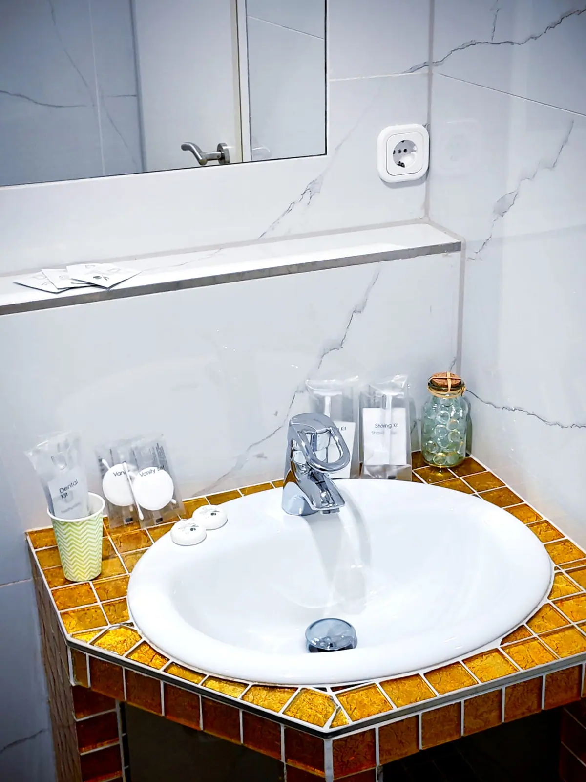 Waschbecken auf goldenem Mosaiksockel mit bereitgelegtem Dental- und Rasier-Set